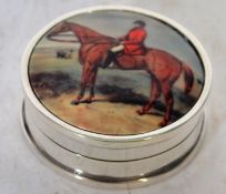 A silver and enamel set pill box with horse and rider.