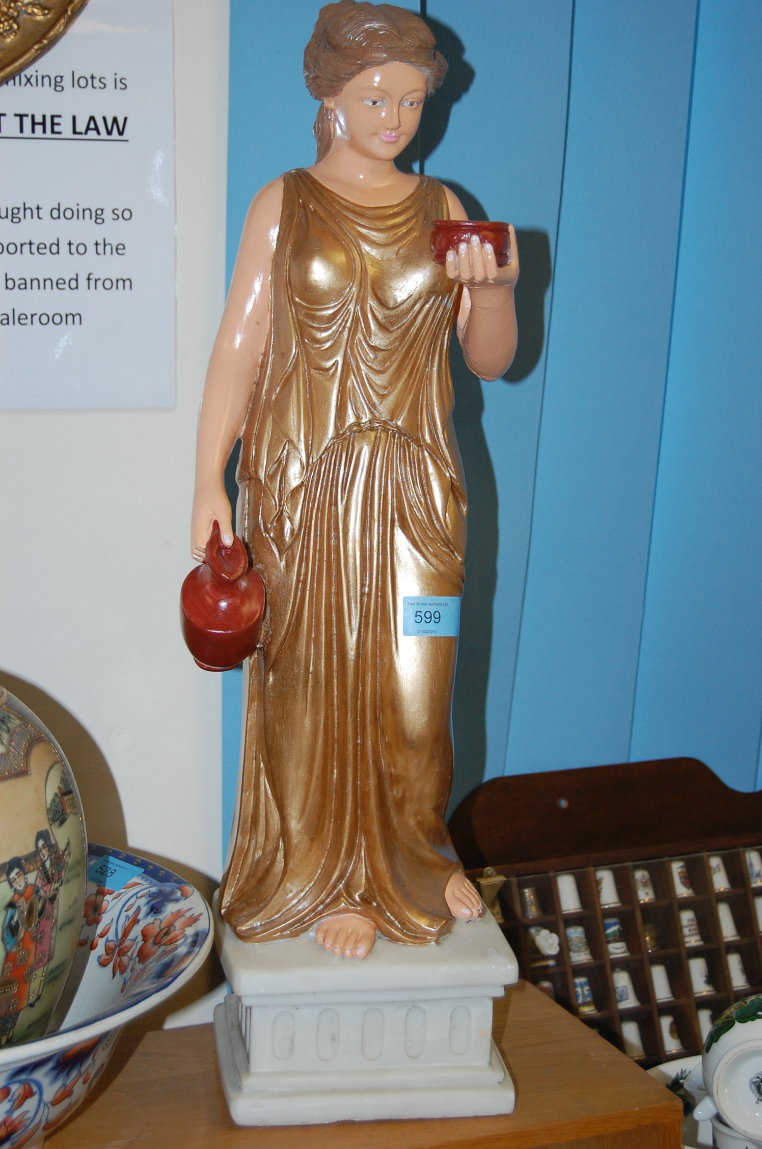 A 20th century marble statue figure of a lady in gold holding a pot.