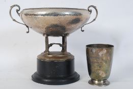A hand beaten trophy/cup on quad feet affixed on top of a ebonised socle along with a Bristol