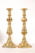 A pair of 19th century large brass pusher candlesticks with tapered columns and sconces atop.