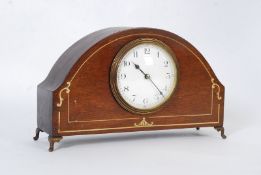 An Edwardian mahogany inlaid mantel clock with French movement, raised on brass feet.