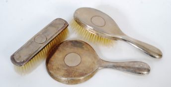 A hallmarked silver dressing mirror together with a silver matching clothes brush and another.