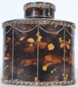 An antique silver plate tea canister with faux tortoiseshell panels encompassing the bottle.