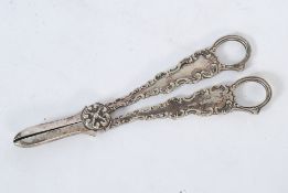 A pair of white silver metal scissors / clippers with detail to handles