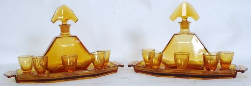 A pair of 1930`s Art Deco amber glass decanter sets comprising decanters, 5 glasses and trays.