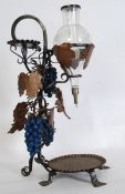 An unusual large wine dispenser. Of wroght metal construction with applied grape vines having glass