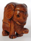 A carved wooden netsuke of an elephant with makers carving to reverse.