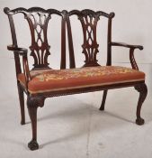 An Edwardian Chippendale revival mahogany twin seat salon chair with needlepoint upholstered seat,
