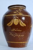 A 19th century terracotta olive storage jar with handpainted finish and arabic style notation to
