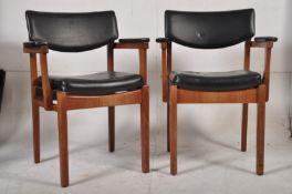 A pair of 1970`s Danish teak wood retro black vinyl carver armchairs. The squared supports having