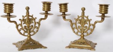 A pair of decorative Indian brass candlesticks depicting Vishnu`s head to centre with twin sconces