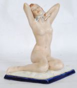 An early 20th century Royal Dux seated nude with raised hands being on a lozenge shaped plinth.