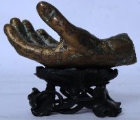 A bronze sculpture of a hand on a carved socle base.