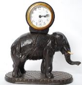 An early 20th century carved elephant carrying an enamel faced 8 day  timepiece clock having