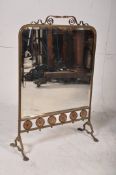 A vintage art nouveau style mirrored fire screen with pressed metal flower decoration to lower strip