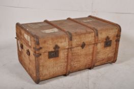 A wooden and canvas bound steamer trunk having hinged clasps, ideal as a coffee table