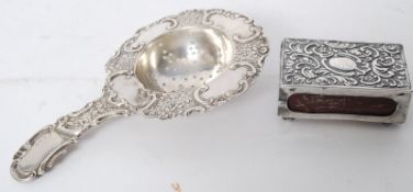 A German hallmarked silver tea strainer together with an English hallmarked rococo matchbox vesta