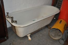 A vintage large cast iron bath being enamel painted and raised on decorative feet