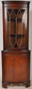 A Georgian style mahogany bow front corner cabinet. Glass display cabinet over cupboard beneath.