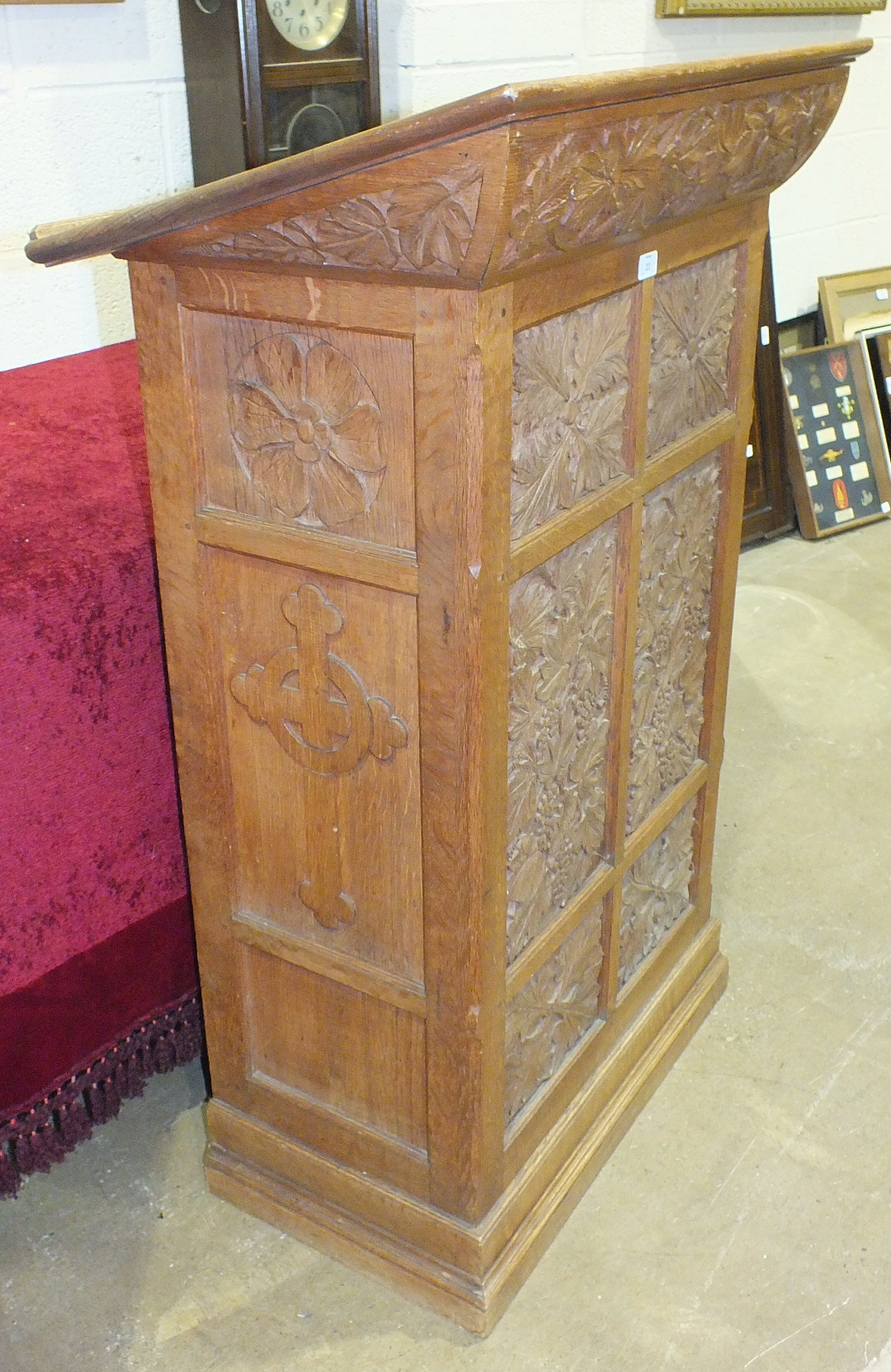 A carved oak lectern carved with acanthus and fruiting vines, the side panels carved with religious