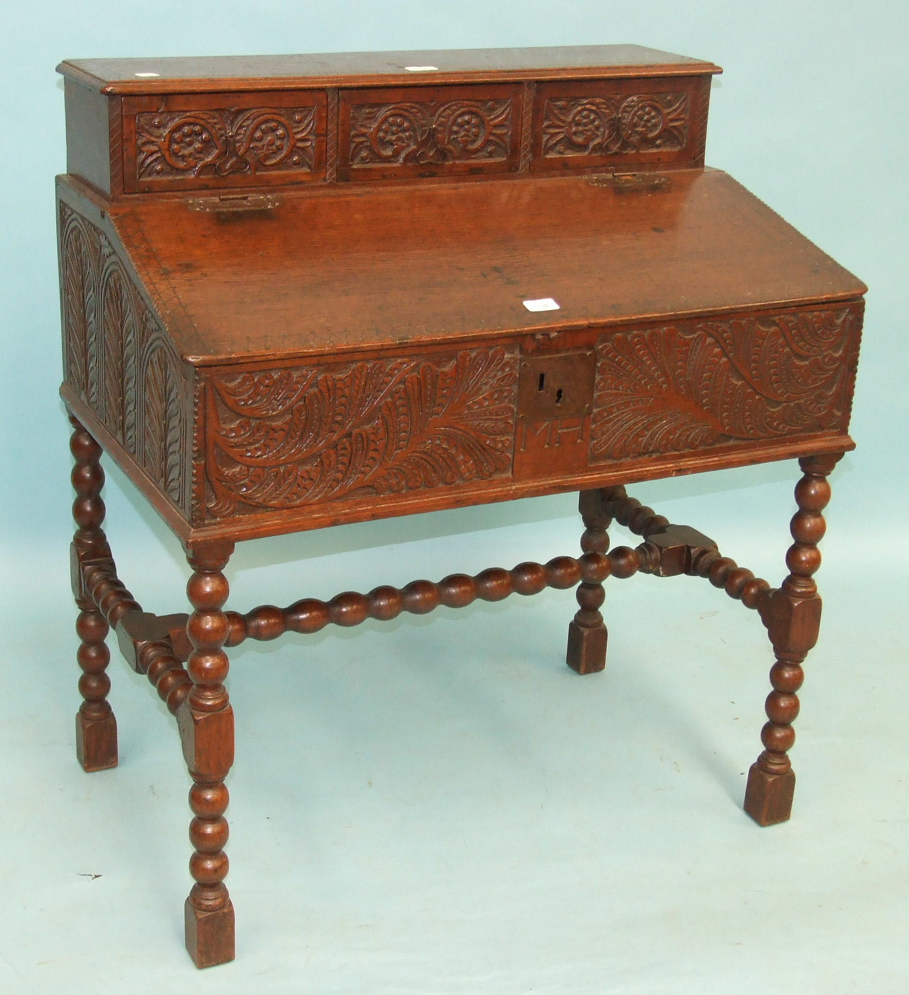 An antique oak bible box, the sloping hinged lid with carved sides and front, on bubble-turned legs