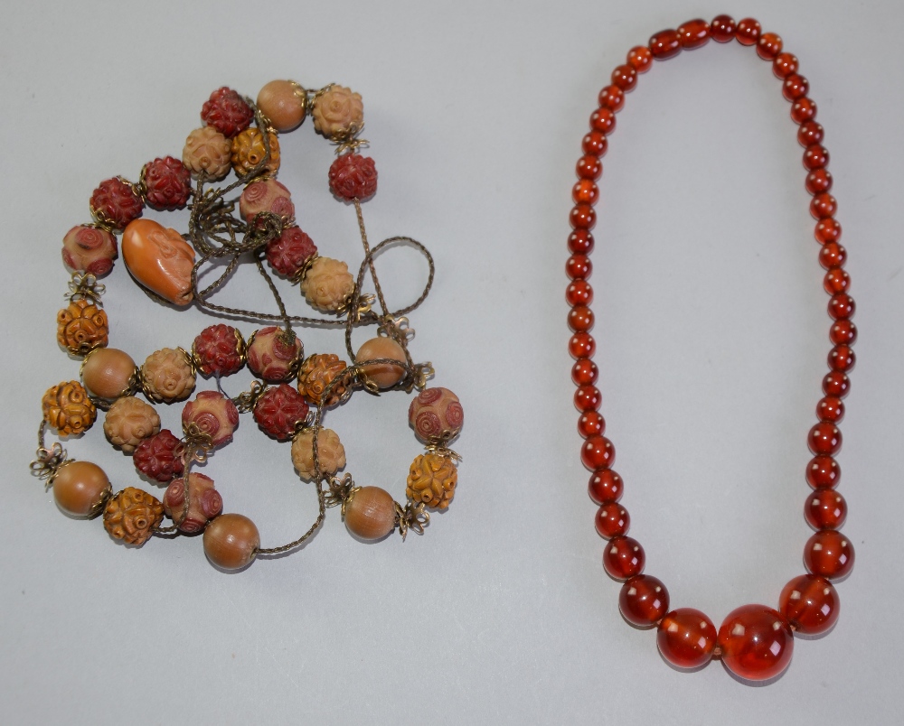 An Amber bead necklace C1900 and another with beads carved in the form of flowers and one carved