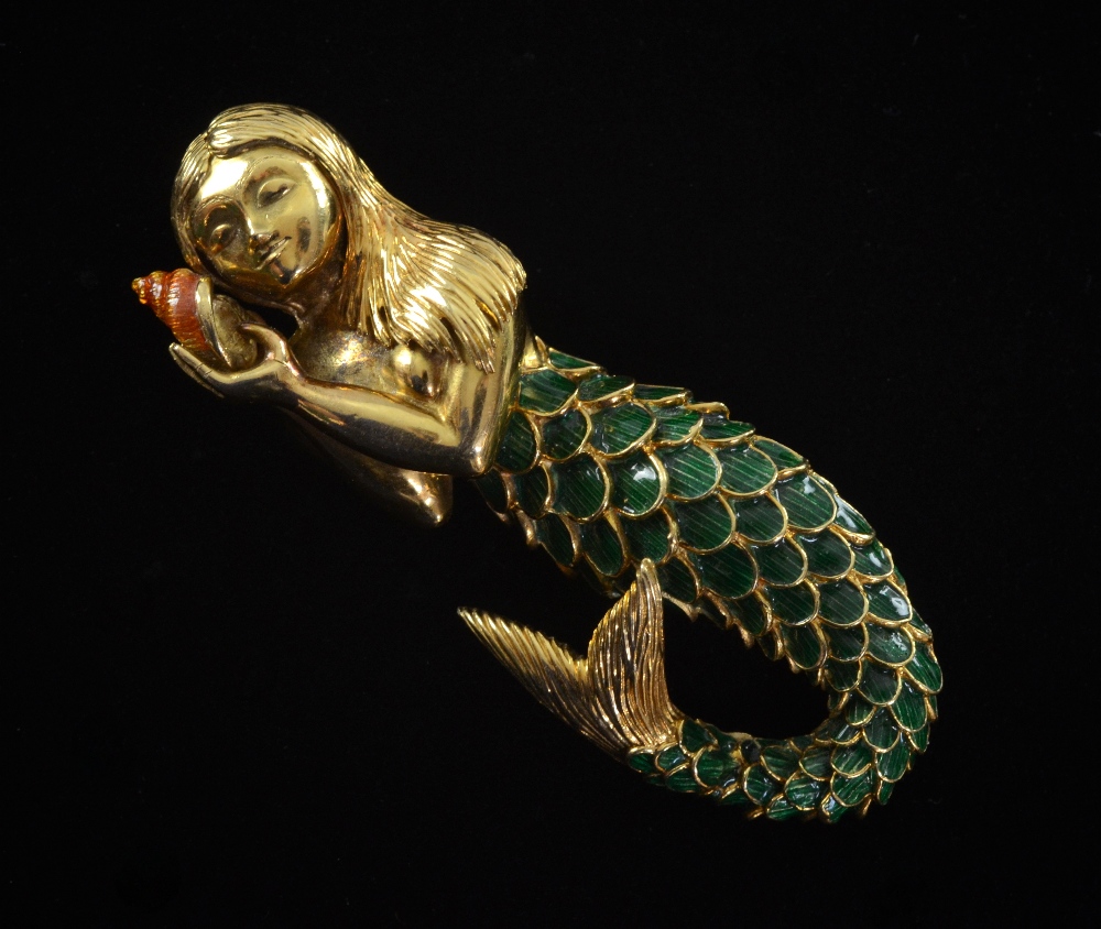 Kutchinsky, a gold and enamel brooch in the form of a mermaid holding a shell, 1970`s , signed