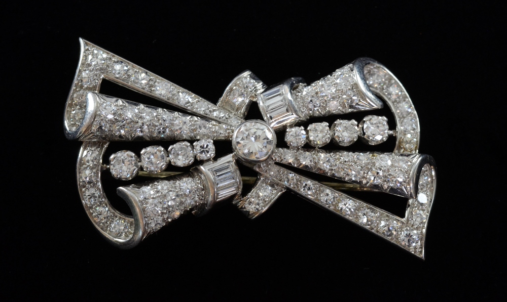 An openwork platinum and diamond bow brooch with principal brilliant cut diamond .4 carat, other