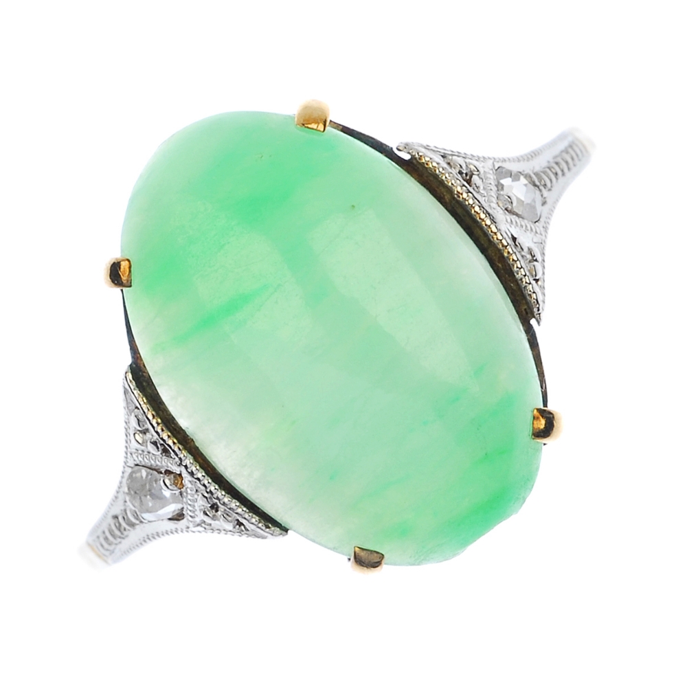 A jade and diamond ring. The oval jade cabochon, with rose-cut diamond shoulders, to the plain