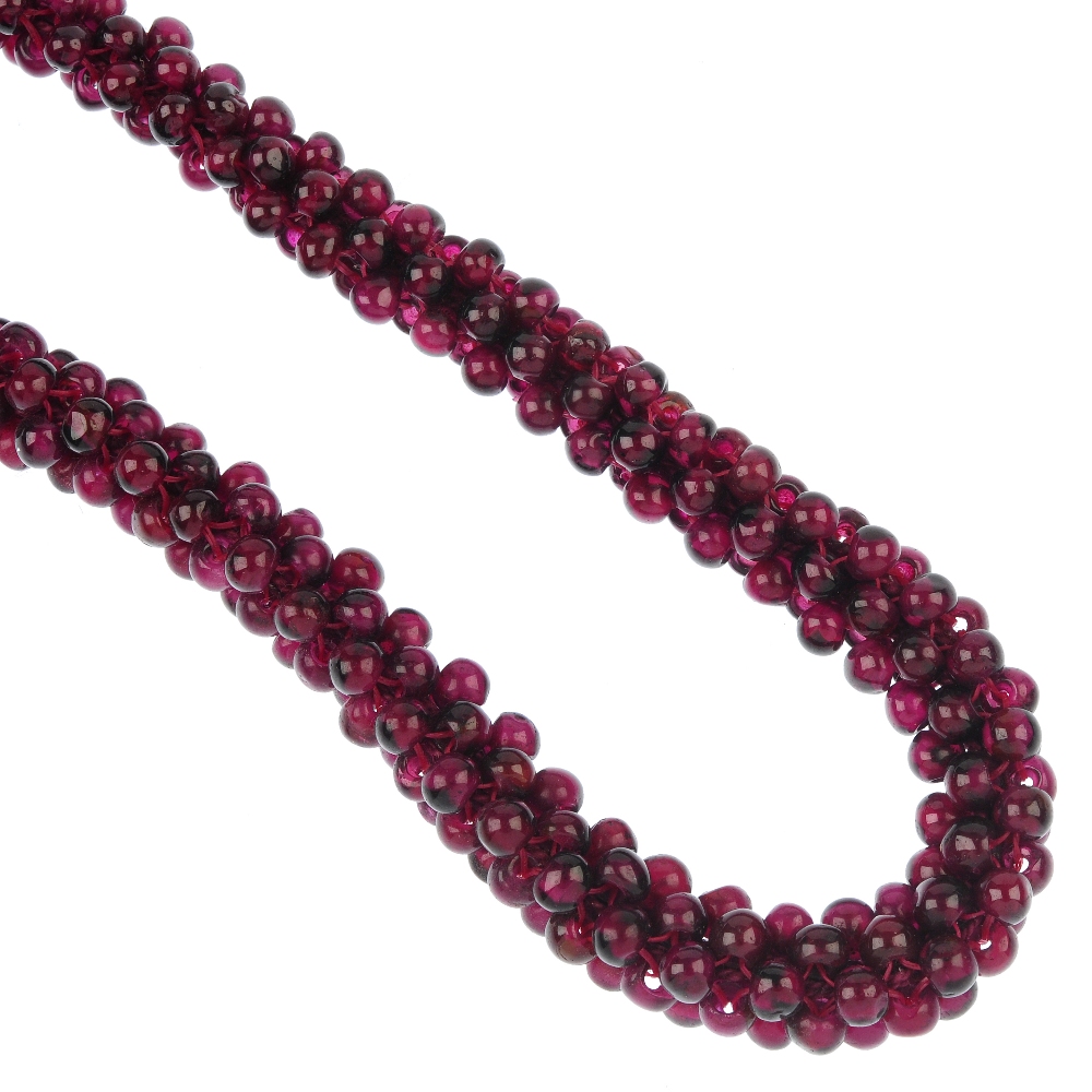 A garnet bead necklace, designed as a woven cord of circular-shape garnet beads. Length 38.5cms.