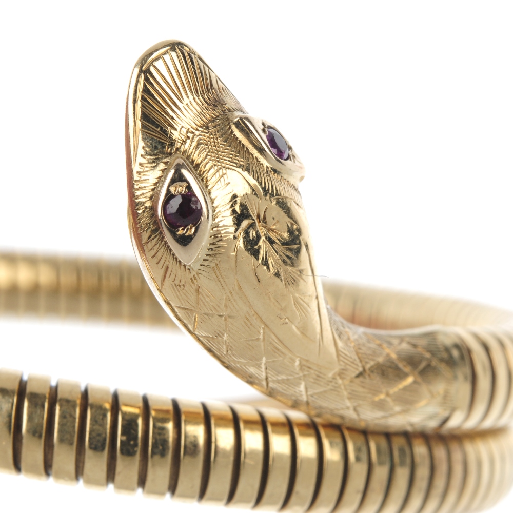 A mid 20th century 9ct gold ruby snake bangle. The engraved head with ruby eyes, to the coiled - Image 2 of 3