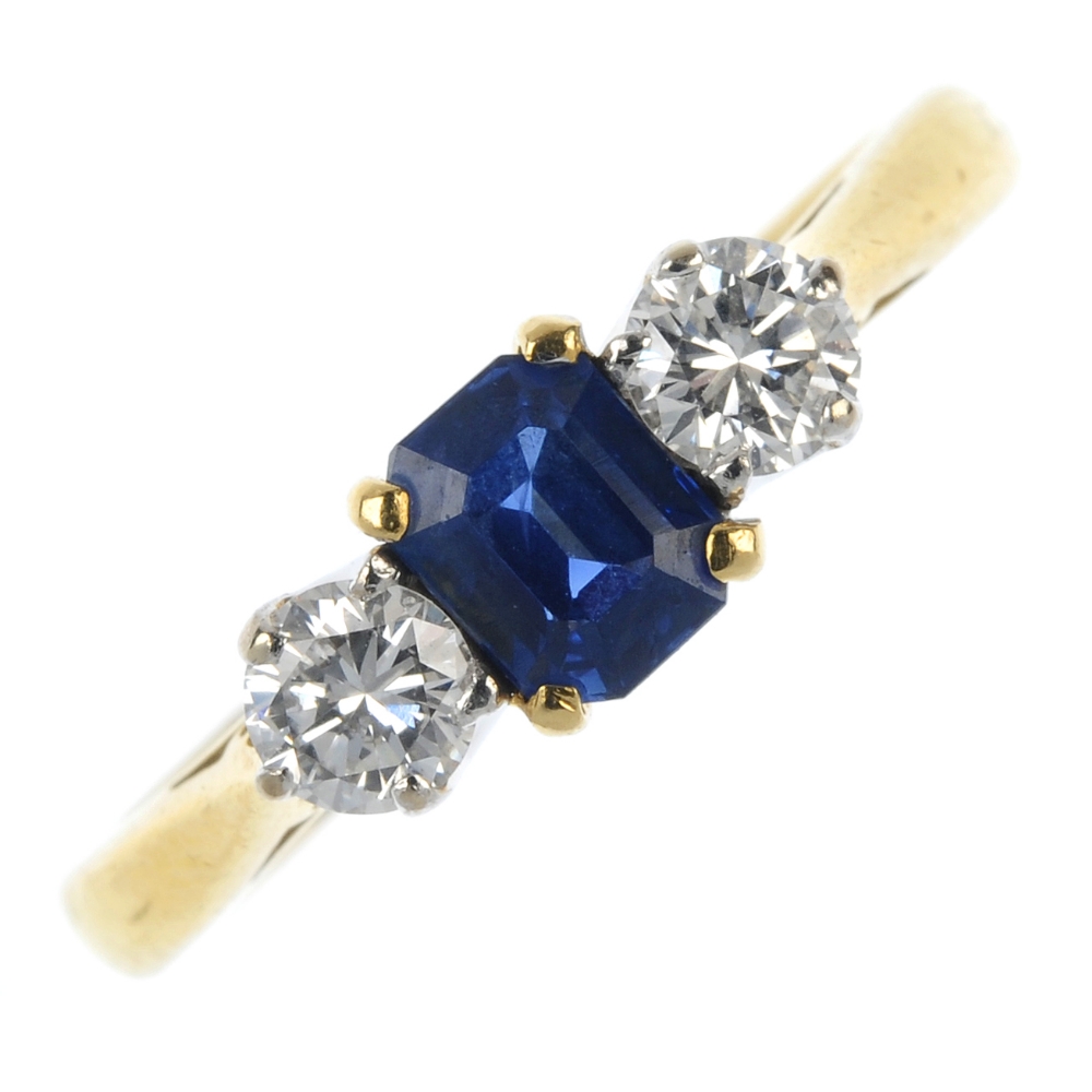 An 18ct gold sapphire and diamond three-stone ring. The rectangular-shape sapphire, with brilliant-