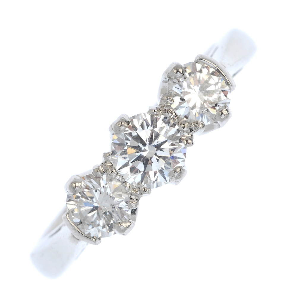 A platinum diamond three-stone ring. The slightly graduated line of brilliant-cut diamonds, to the