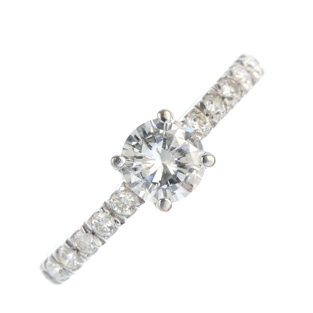 A diamond single-stone ring. The brilliant-cut diamond, with brilliant-cut diamond shoulders, to