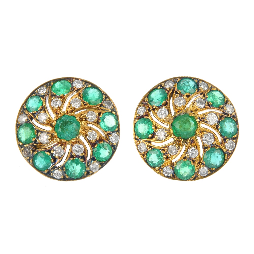 A pair of emerald and diamond earrings. Each of openwork design, the circular-shape emerald, within