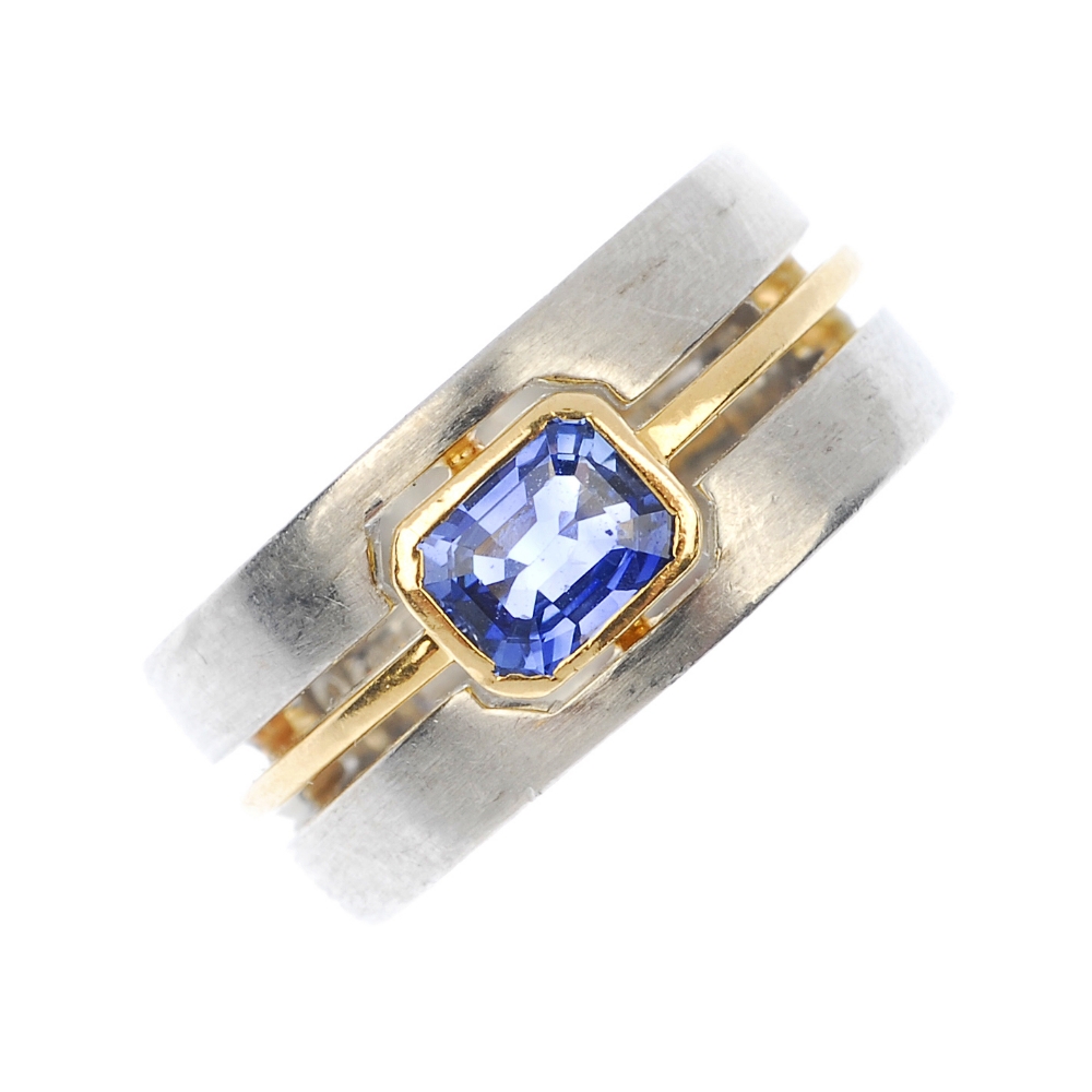 A sapphire single-stone band ring. Of bi-colour design, the rectangular-shape sapphire collet, to