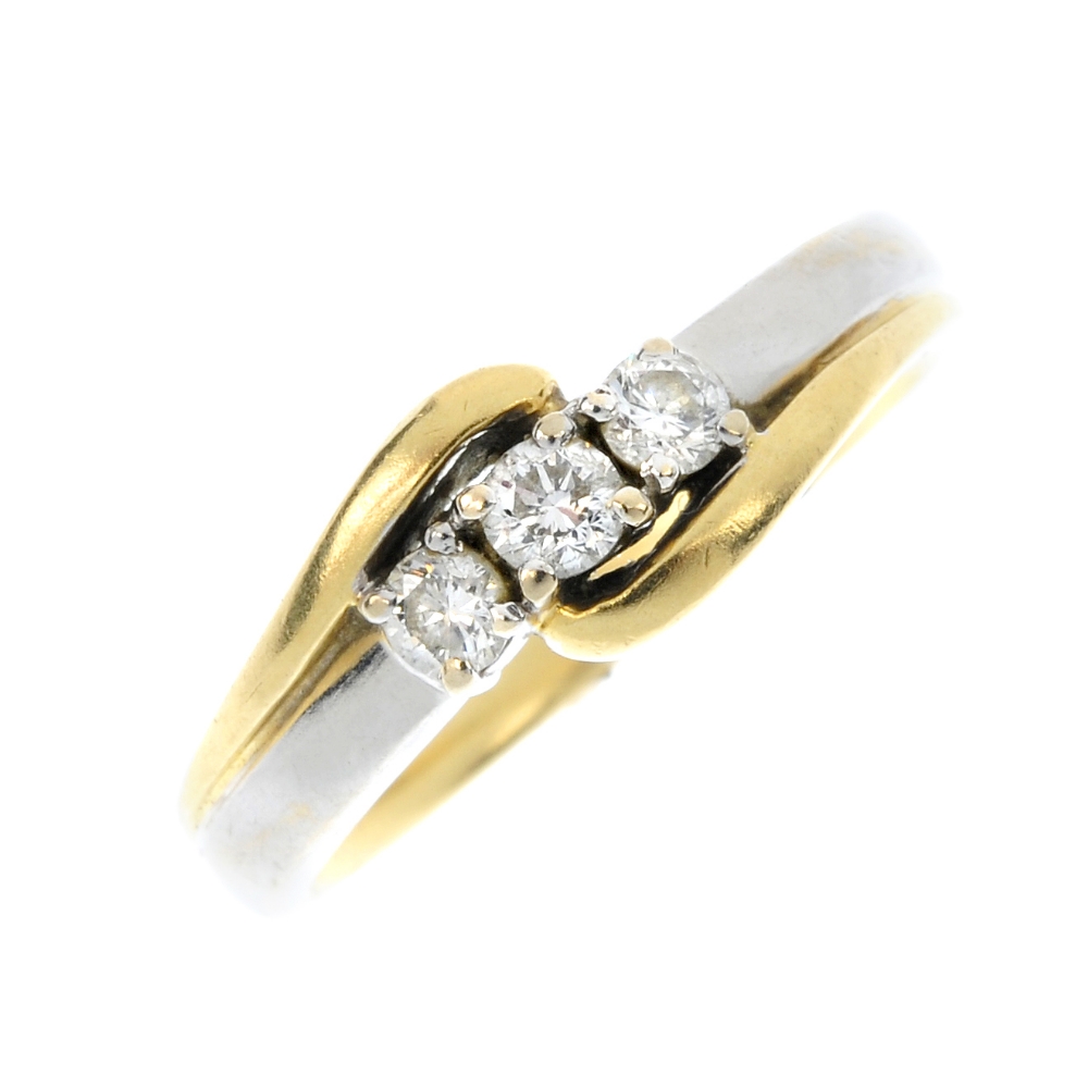 An 18ct gold diamond three-stone ring. Of bi-colour design, the slightly graduated brilliant-cut