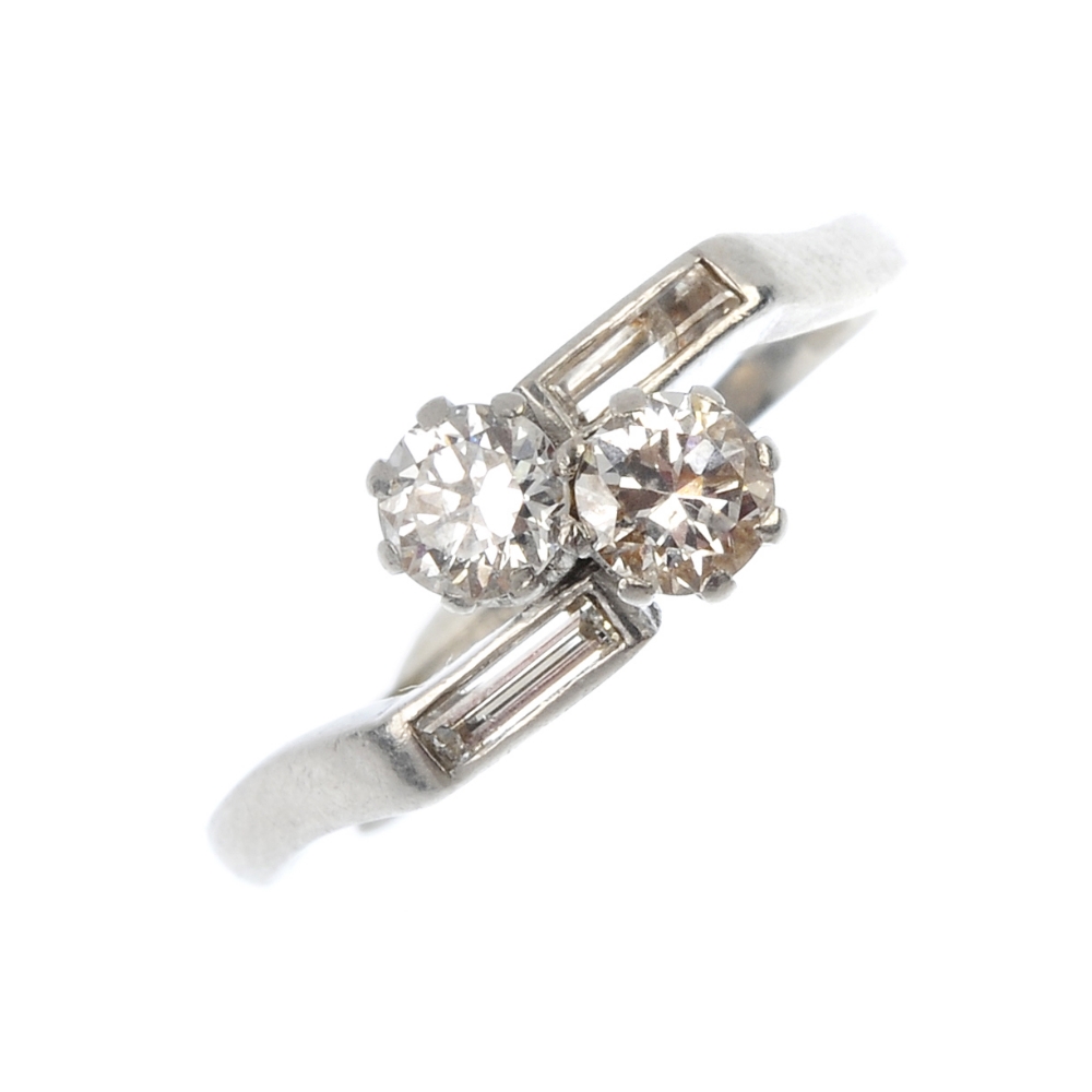 An early 20th century platinum diamond two-stone crossover ring. The two circular-cut diamonds, to