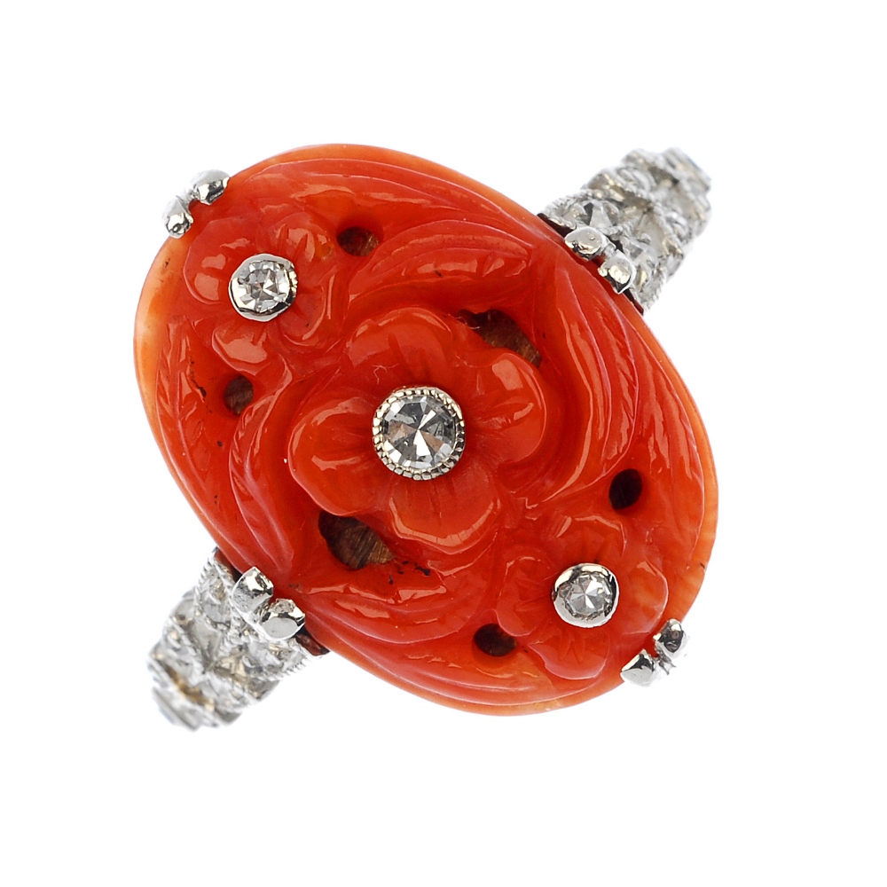 A coral and diamond ring. The floral carved oval-shape coral panel, with single-cut diamond collet