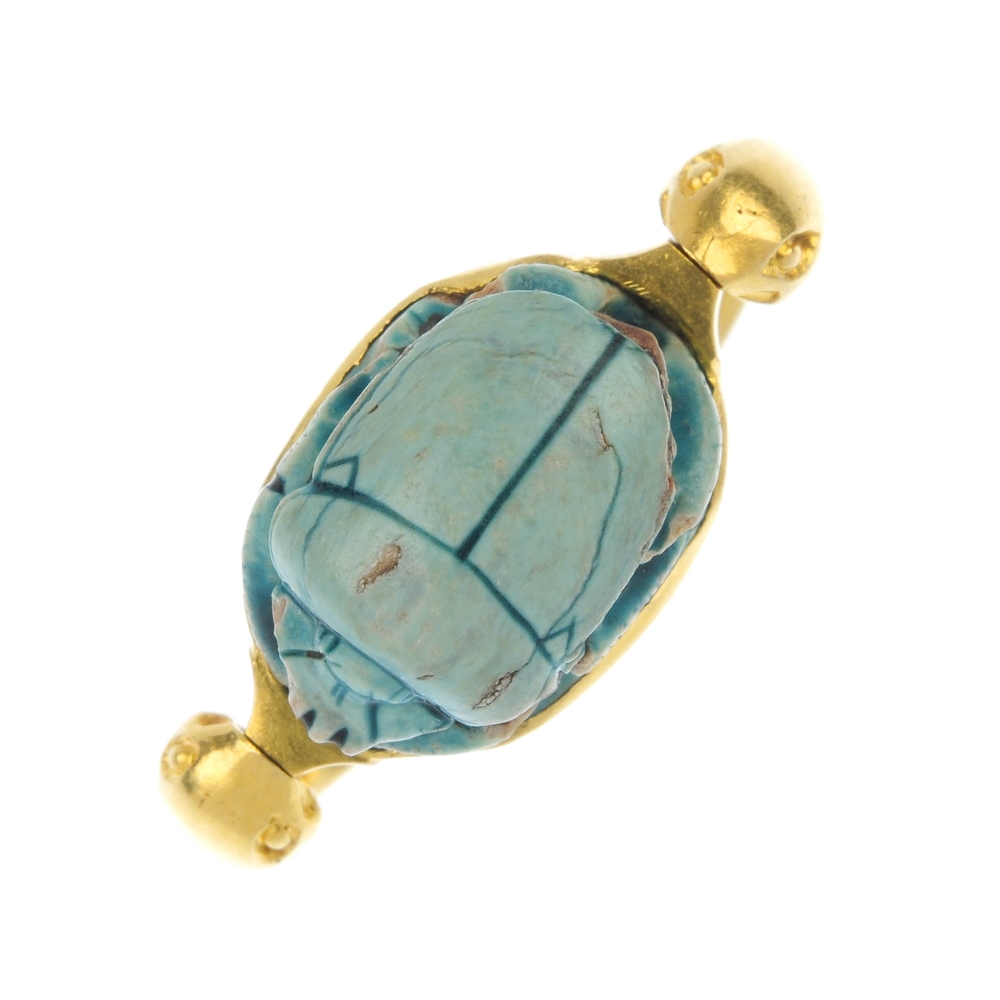 An early 20th century gold scarab ring. The glazed faience scarab beetle, within a collet mount,