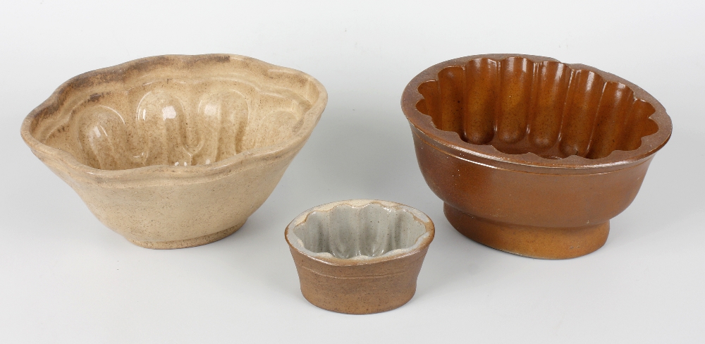 A collection of pottery jelly moulds to include a creamware spiral example, various stonewares with