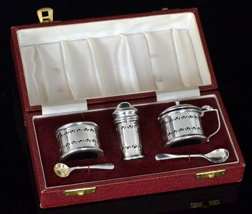 A cased hallmarked silver three piece cruet set of circular form with pierced details and blue
