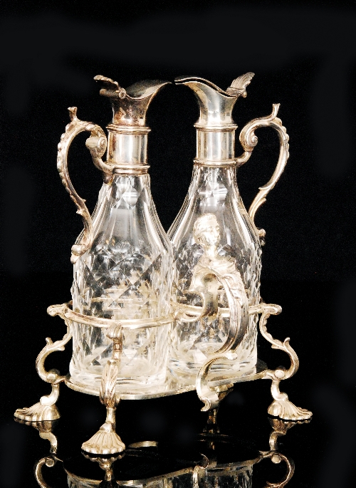 A George III hallmarked silver twin oil bottle stand with scroll handle terminating in a Classical