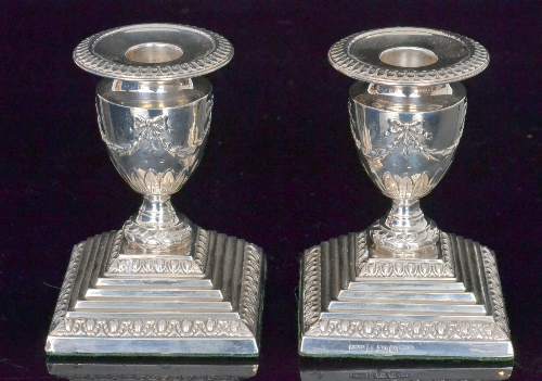 A pair of hallmarked silver piano candlesticks, square stepped bases below circular sconces
