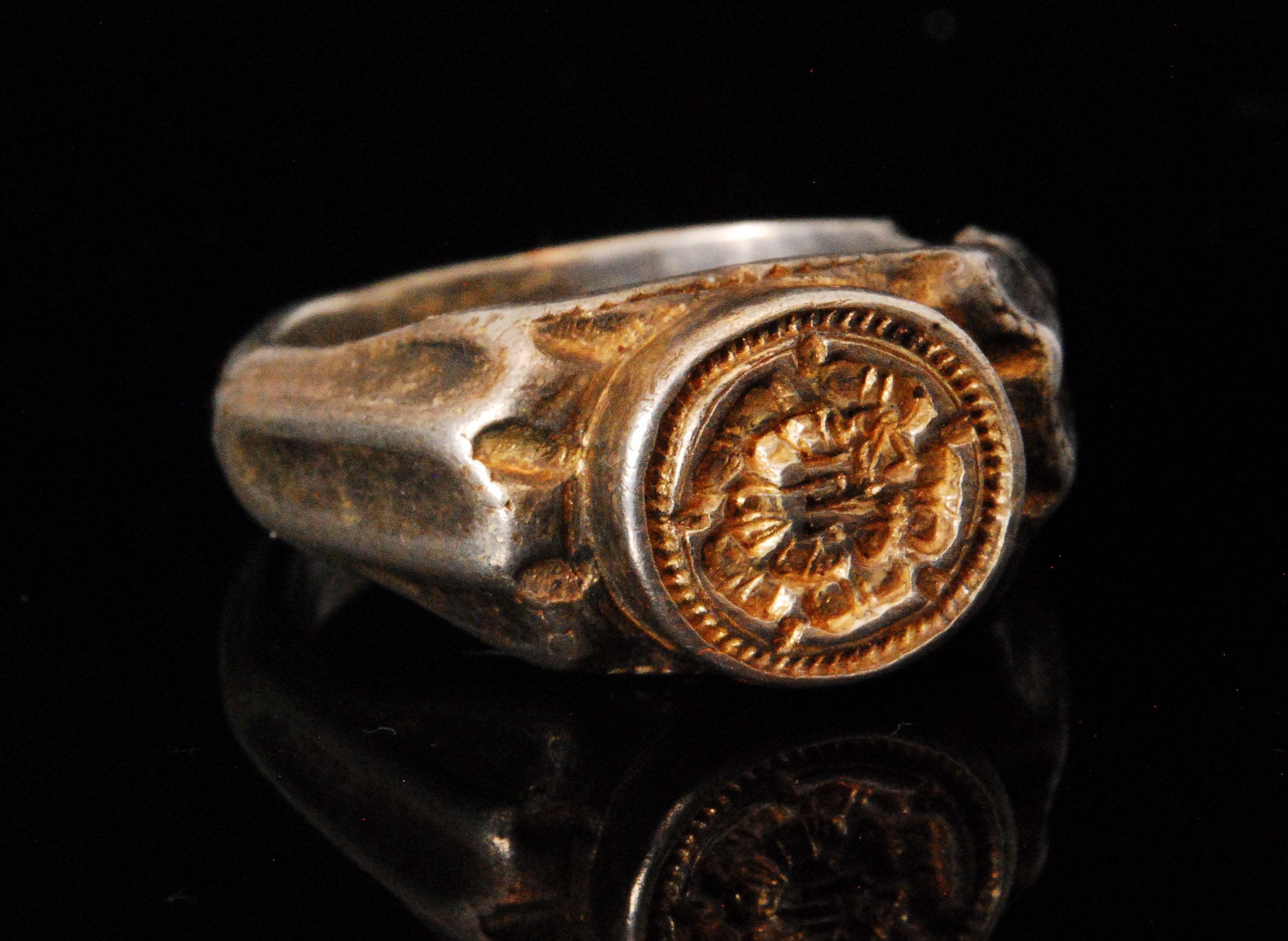 A Tudor Renaissance period silver ring centred with a rose within a dot decorated border flanked by