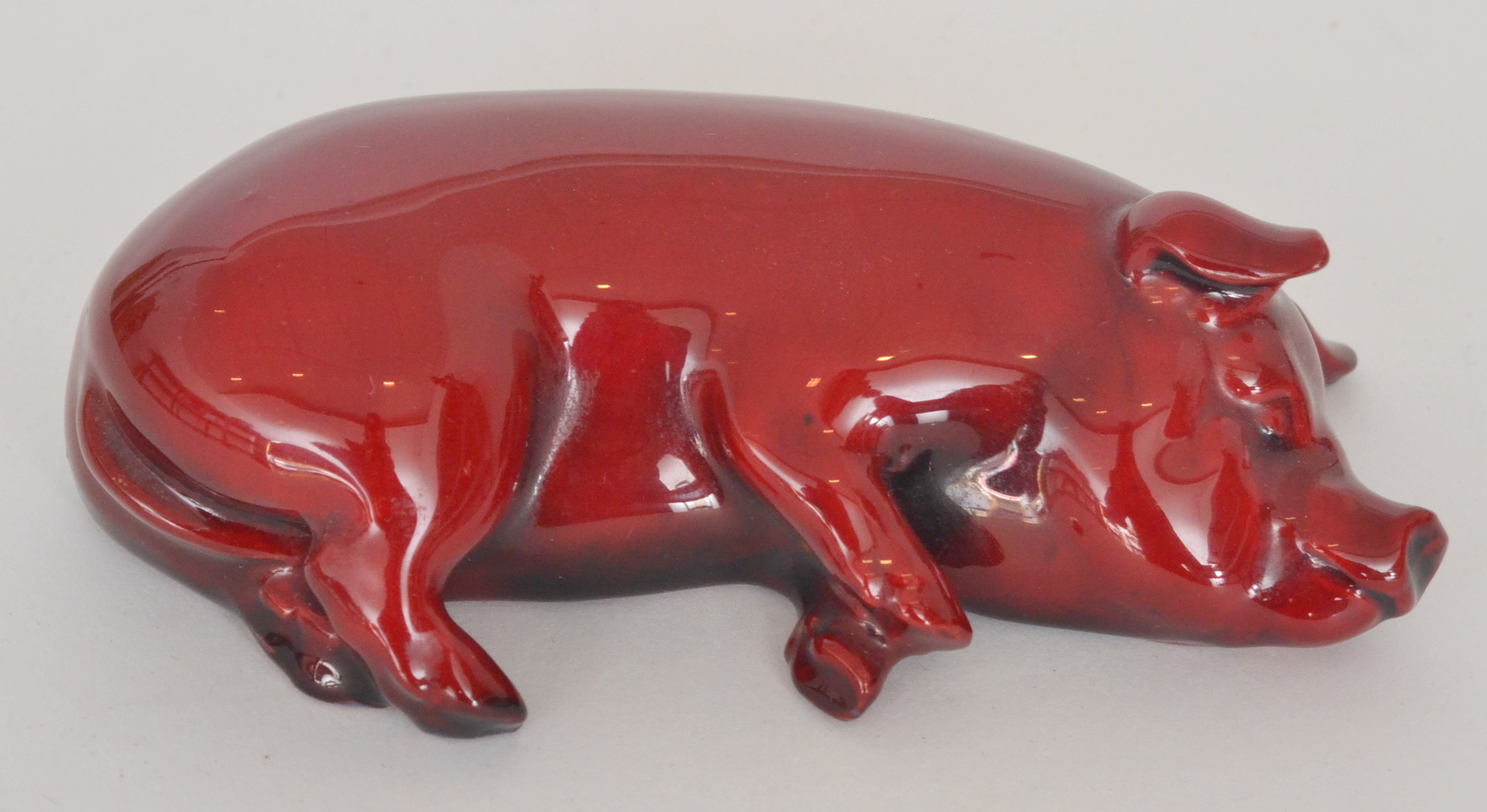 A Royal Doulton flambe pig modelled sleeping on its side, printed marks