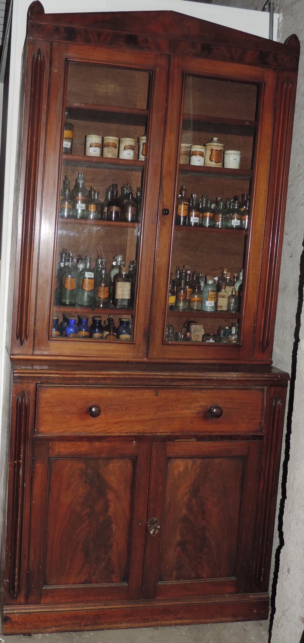 A tall Victorian mahogany Bookcase, the pointed cornice over two glazed doors, a large frieze drawer