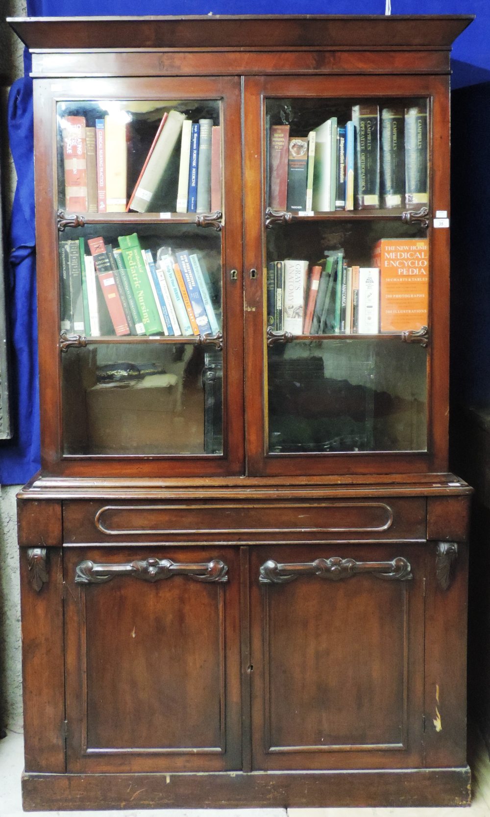 A small carved two door Victorian mahogany Bookcase, with frieze drawer. (1)