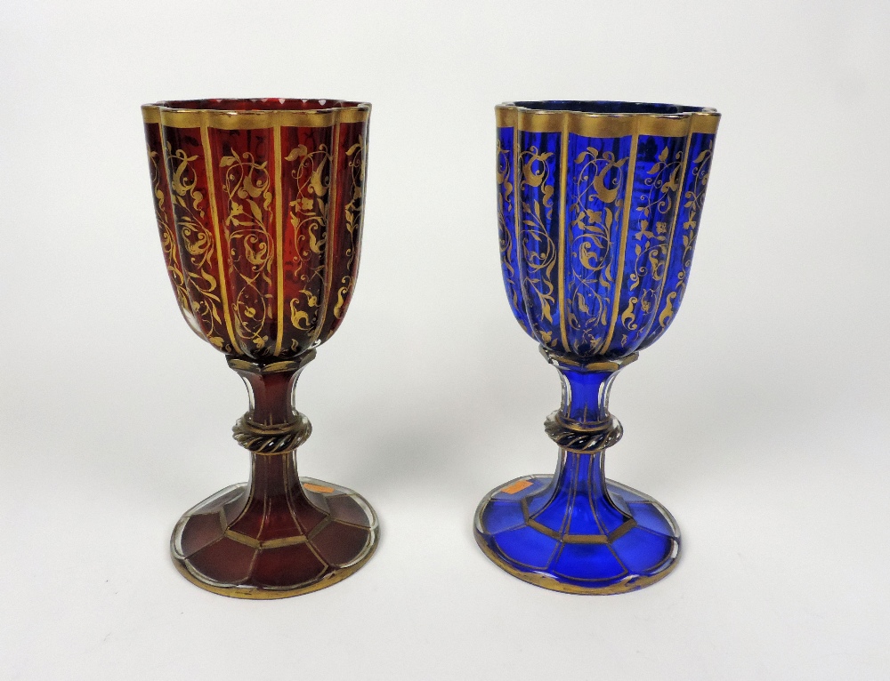 An unusual pair of 19th Century Bohemian glass red and blue Goblets, with overall gilt decoration,