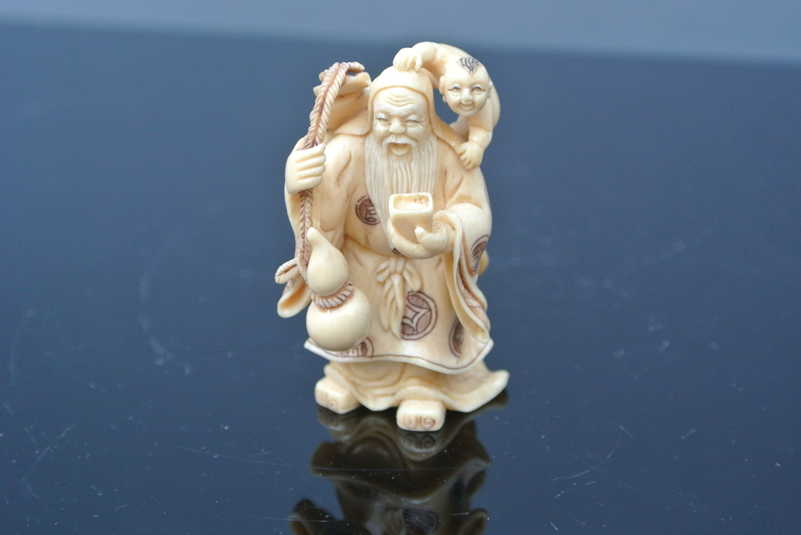 Japan School 19th century. A finely executed carved ivory sculpture of a man carrying a child on